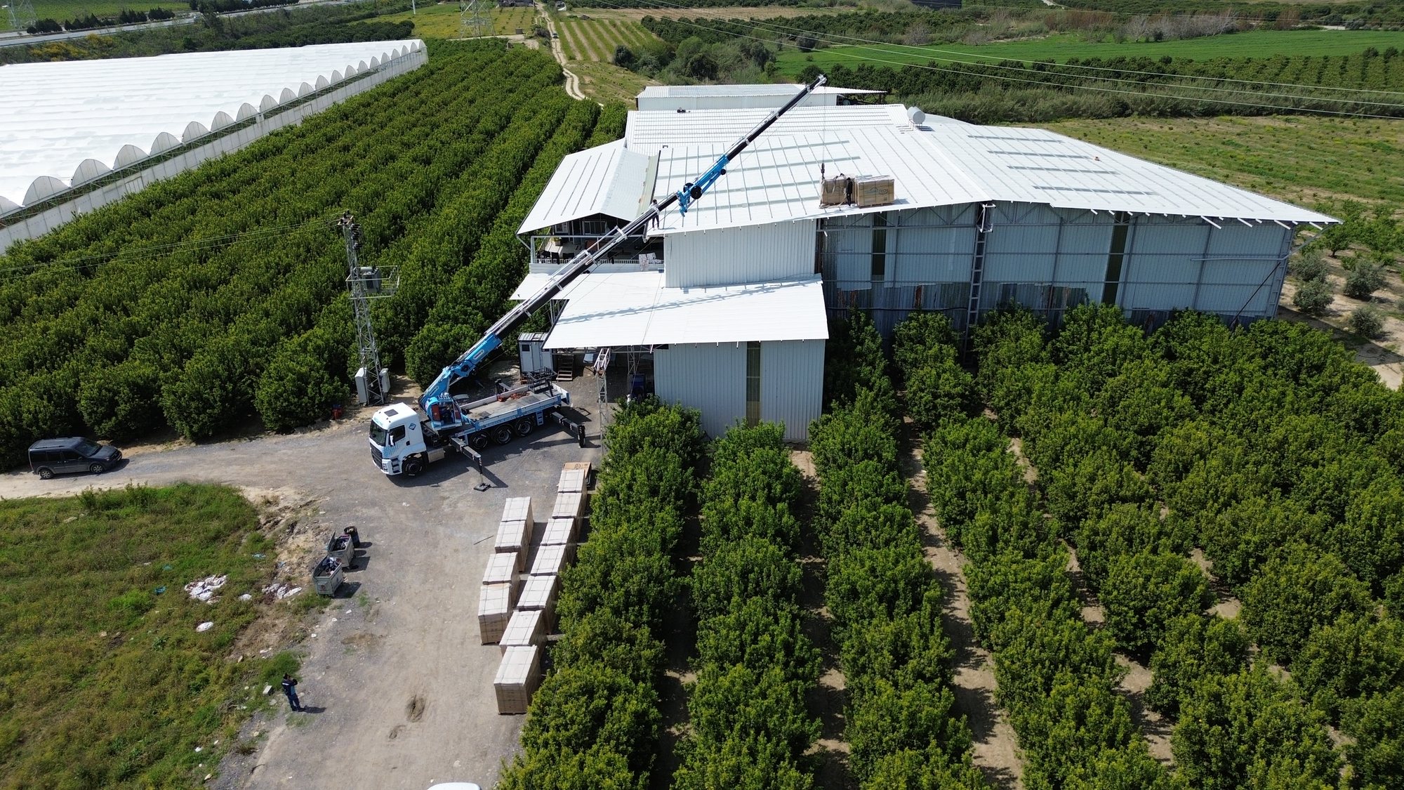 Pandora Enerji — Oğuzlar Gıda Mersin çatı tipi GES kurulumu sırasında çatıya vinçle malzeme taşınıyor, drone görünümü